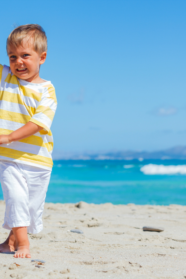 Маленький мальчик на пляже с игрушечным самолетом в руках