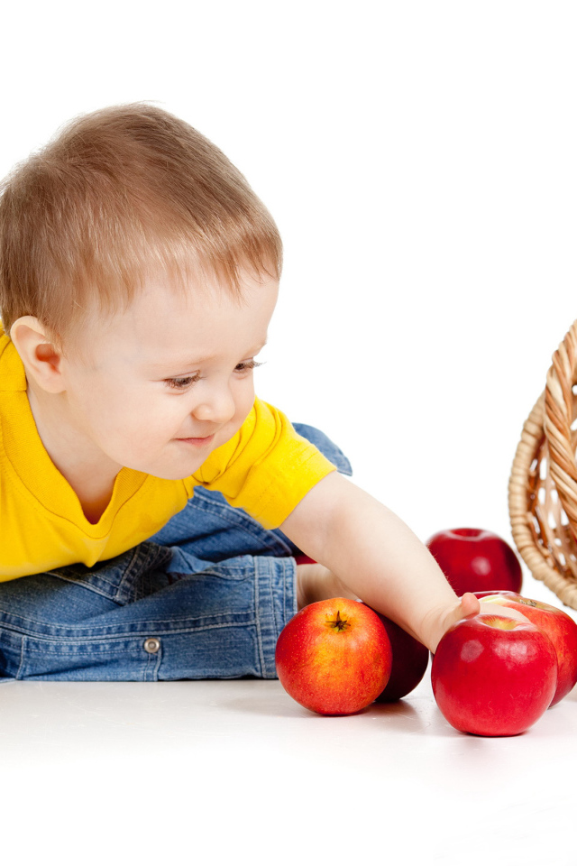 Маленький мальчик с корзиной спелых яблок на белом фоне