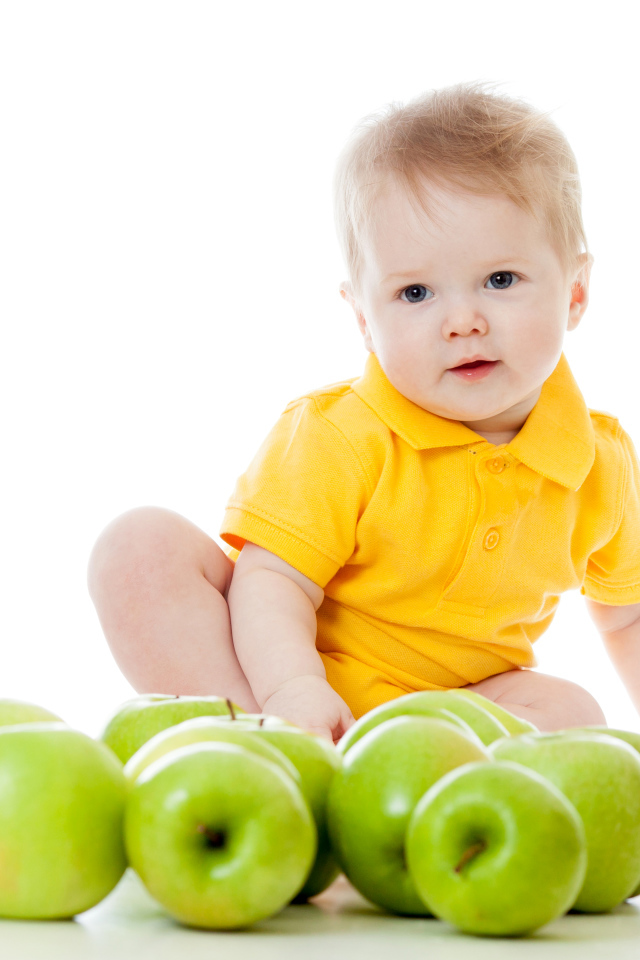 Маленький мальчик с зелеными яблоками на белом фоне
