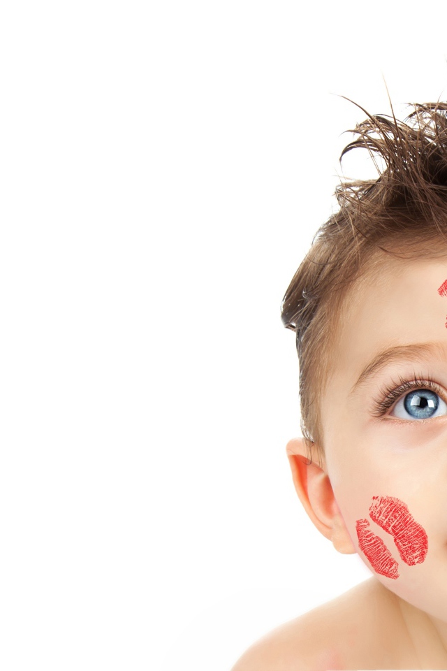 Маленький мальчик со следами от поцелуев на лице на белом фоне