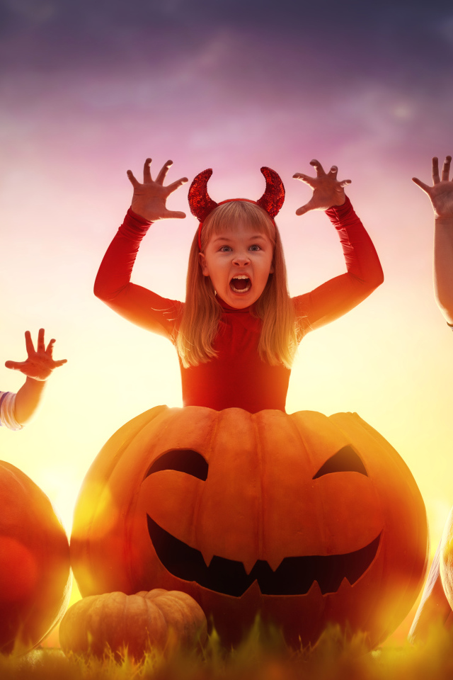 Маленькие дети в костюмах на Хэллоуин с большими тыквами