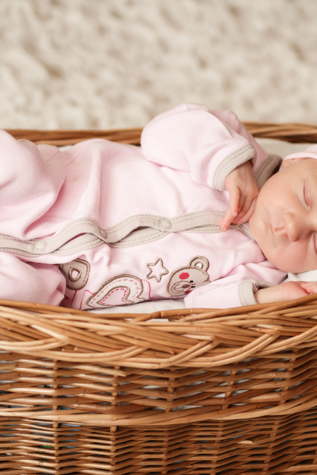 Маленькая милая девочка спит в большой корзине