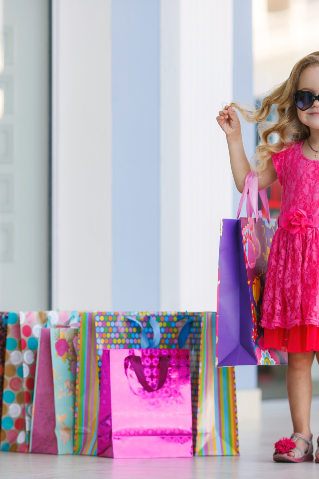 Маленькая модная девочка в красном платье с покупками