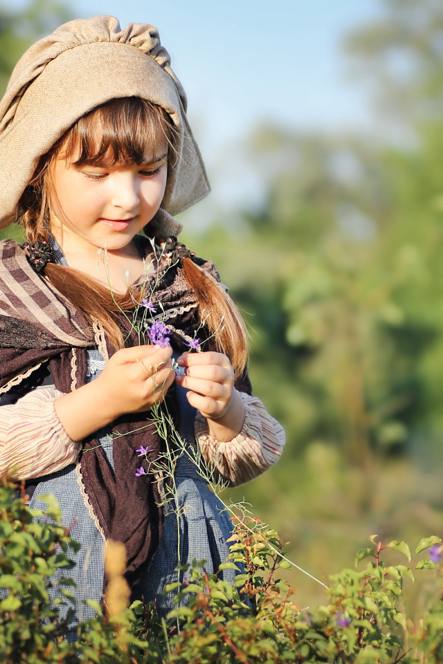 Маленькая девочка в костюме собирает травы