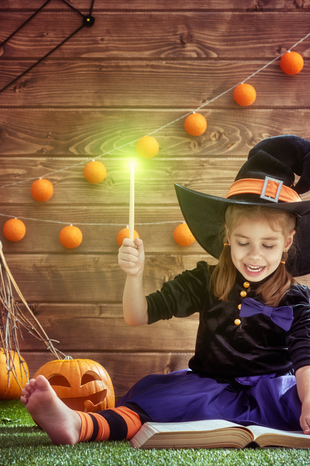 Маленькая девочка в костюме ведьмы с волшебной книгой на Хэллоуин