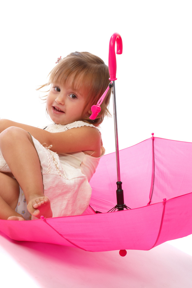 Маленькая девочка сидит в розовом зонте на белом фоне