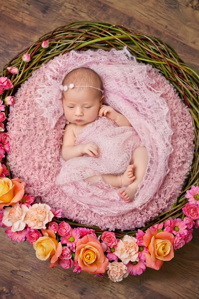 Маленькая девочка спит в корзине украшенной цветами