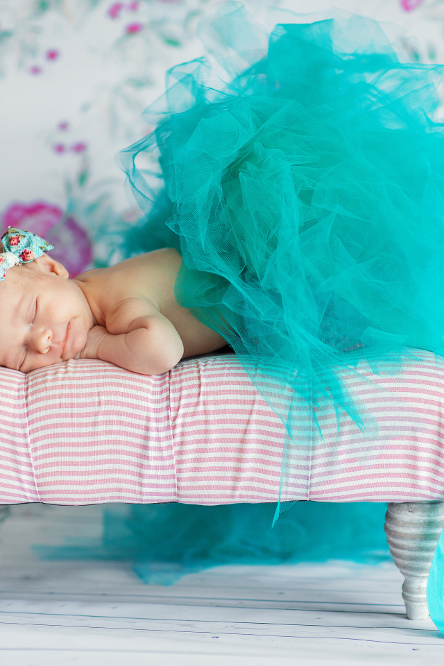 Маленькая девочка спит в красивом бирюзовом платье