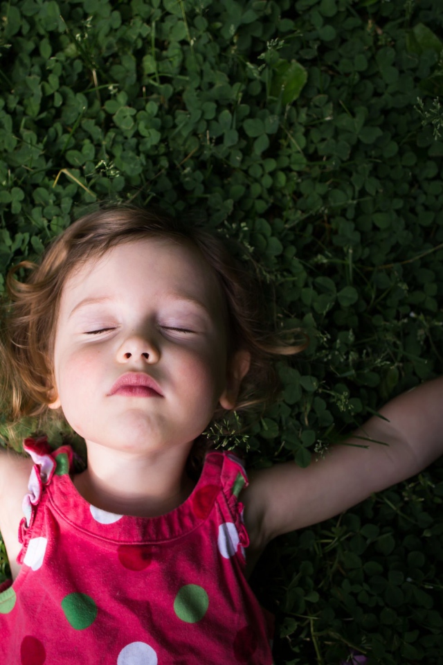Маленькая девочка спит на зеленой траве 