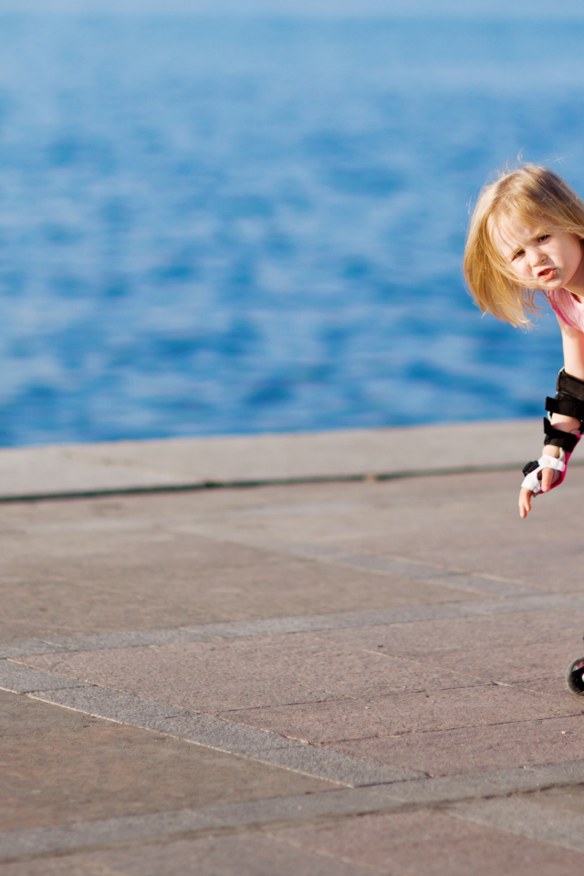 Маленькая девочка катается на роликах на побережье