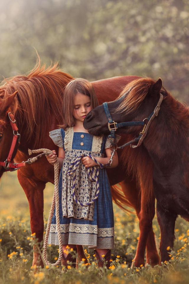 Маленькая девочка гуляет по полю с маленькими пони