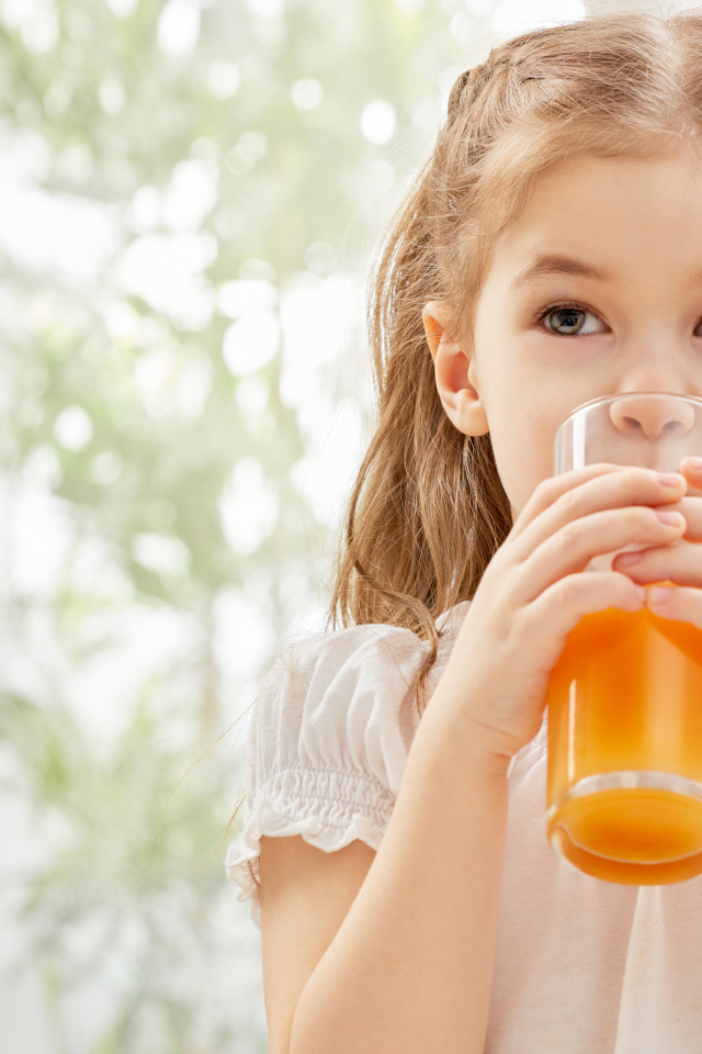 Маленькая девочка со стаканом сока в руках