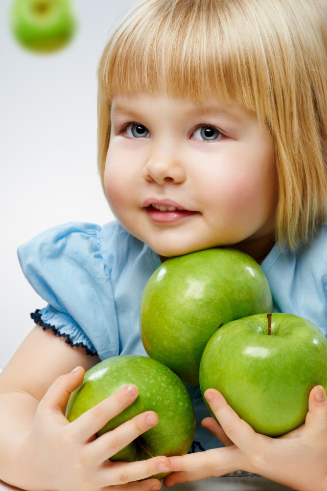 Маленькая девочка с зелеными яблоками в руках