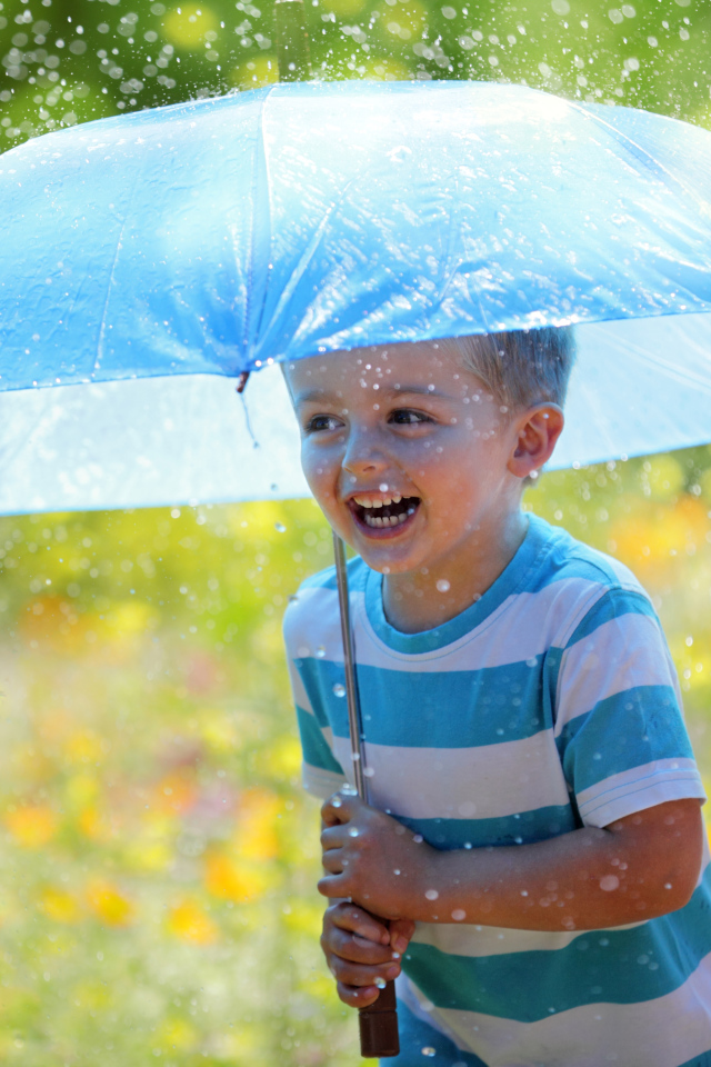 Маленький улыбающийся мальчик с голубым зонтом под дождем