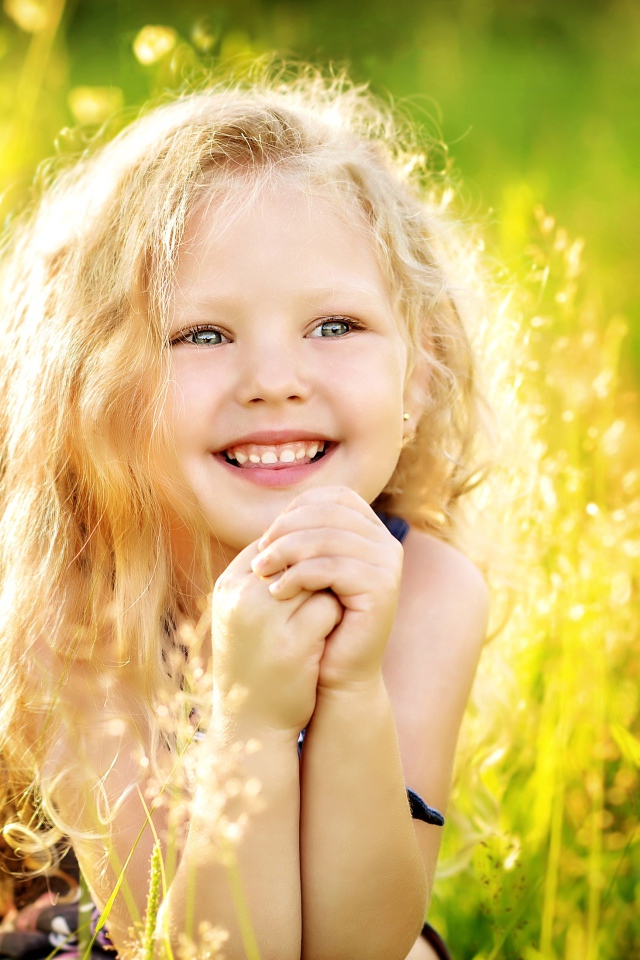 Маленькая улыбающаяся девочка в лучах солнца