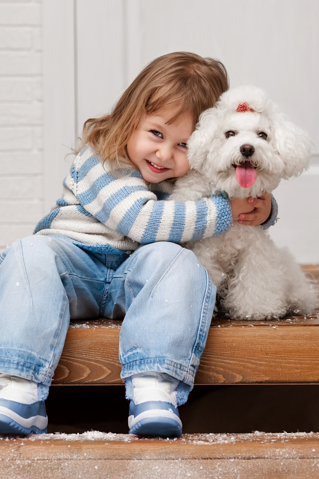 Маленькая улыбающаяся девочка сидит с белым пуделем на ступеньках