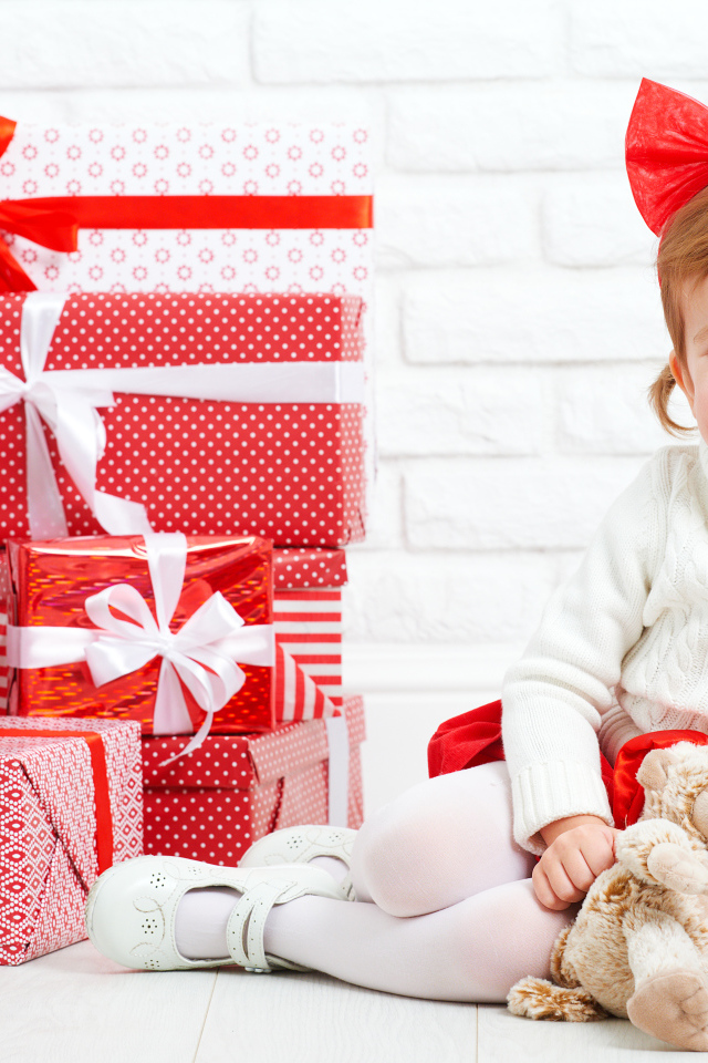 Маленькая улыбающаяся девочка с подарками на новый год