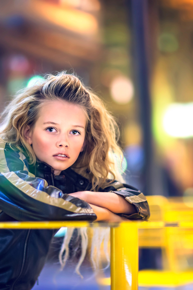 Длинноволосая девочка сидит на карусели