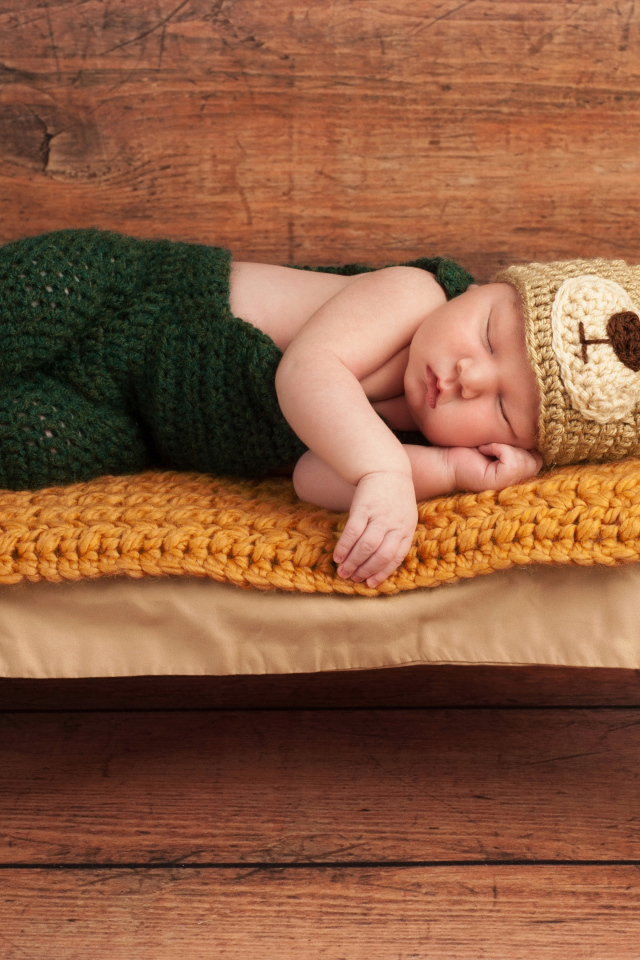 Новорожденный ребенок в костюме медвежонка спит на крошечной кровати