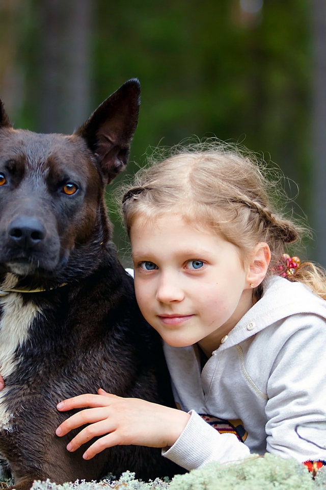 Милая голубоглазая девочка с большой черной собакой