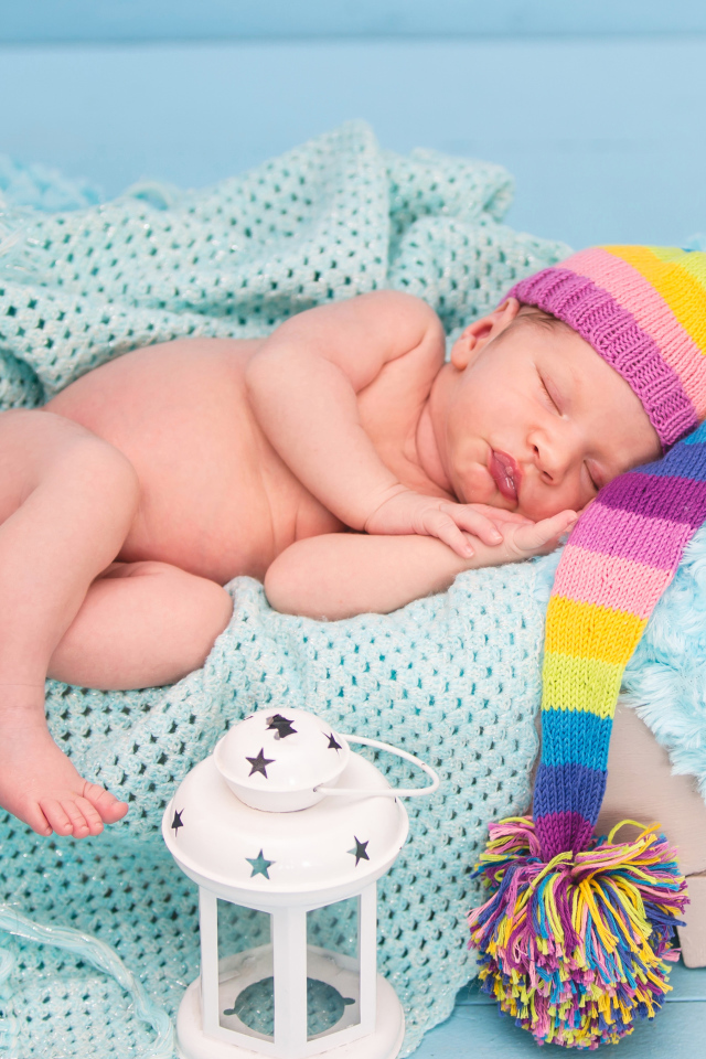 Спящий грудной ребенок в большой вязаной шапке