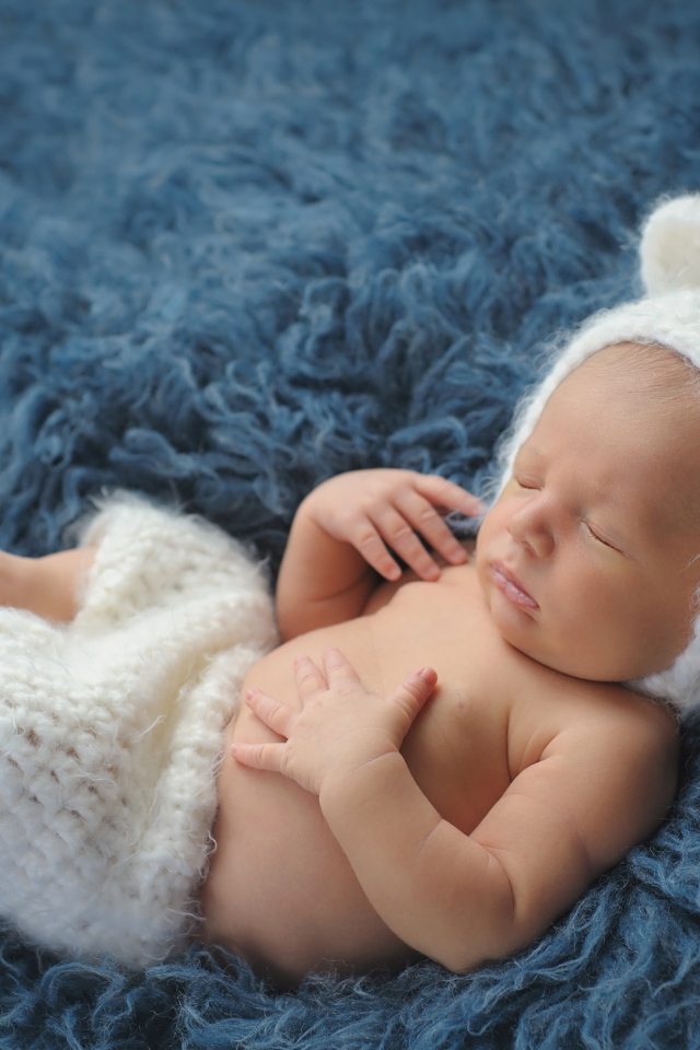 Спящий грудной ребенок в белом костюме медвежонка