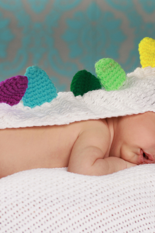 Спящий младенец в белой вязаной накидке
