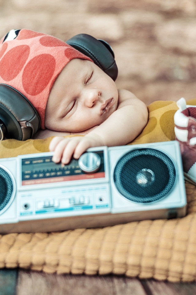 Спящий младенец в наушниках и с игрушечным магнитофоном