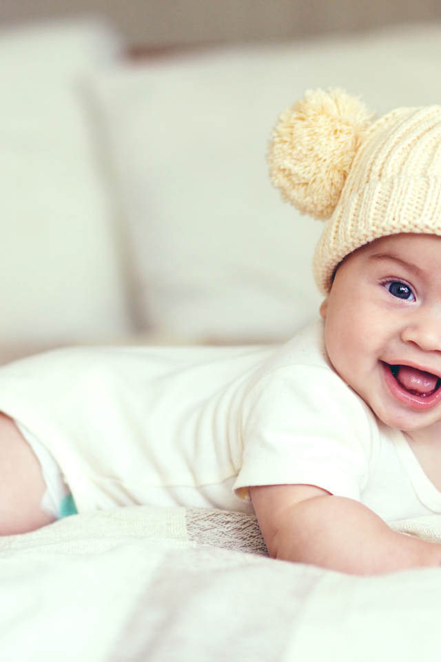 Улыбающийся грудной ребенок в забавной вязаной шапке