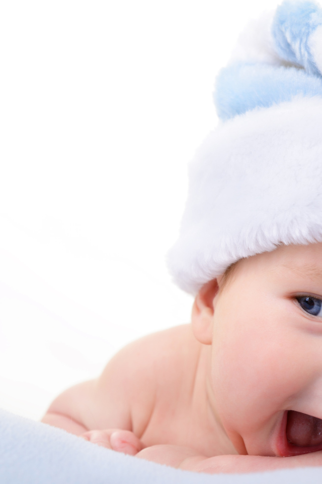 Улыбающийся грудной ребенок в голубой новогодней шапке