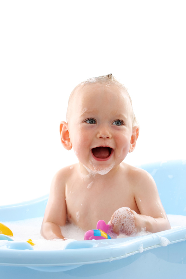 Улыбающийся грудной ребенок сидит в синей ванночке на белом фоне