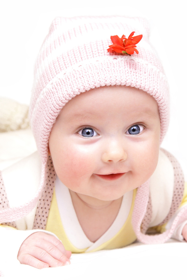 Улыбающийся голубоглазый малыш в розовой шапке