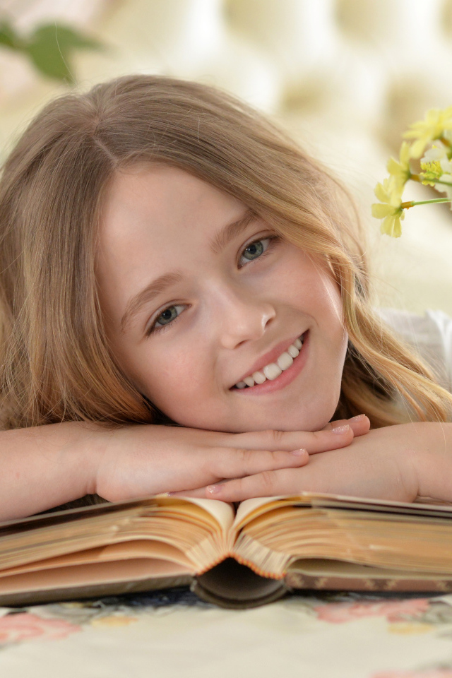 Улыбающаяся русоволосая девочка с книгой