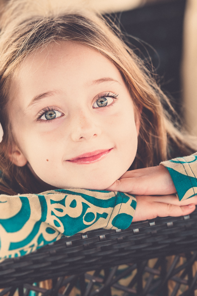 Улыбающаяся зеленоглазая девочка с белым цветком в волосах