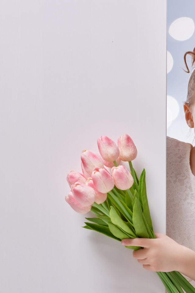 Улыбающаяся маленькая девочка с букетом розовых тюльпанов