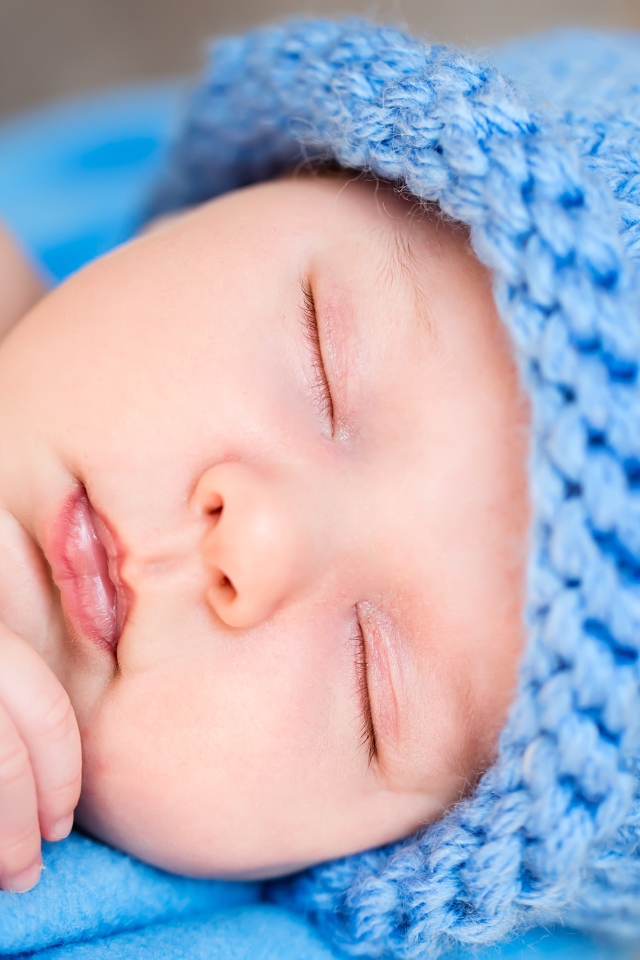 Милый спящий младенец с синей вязаной шапке