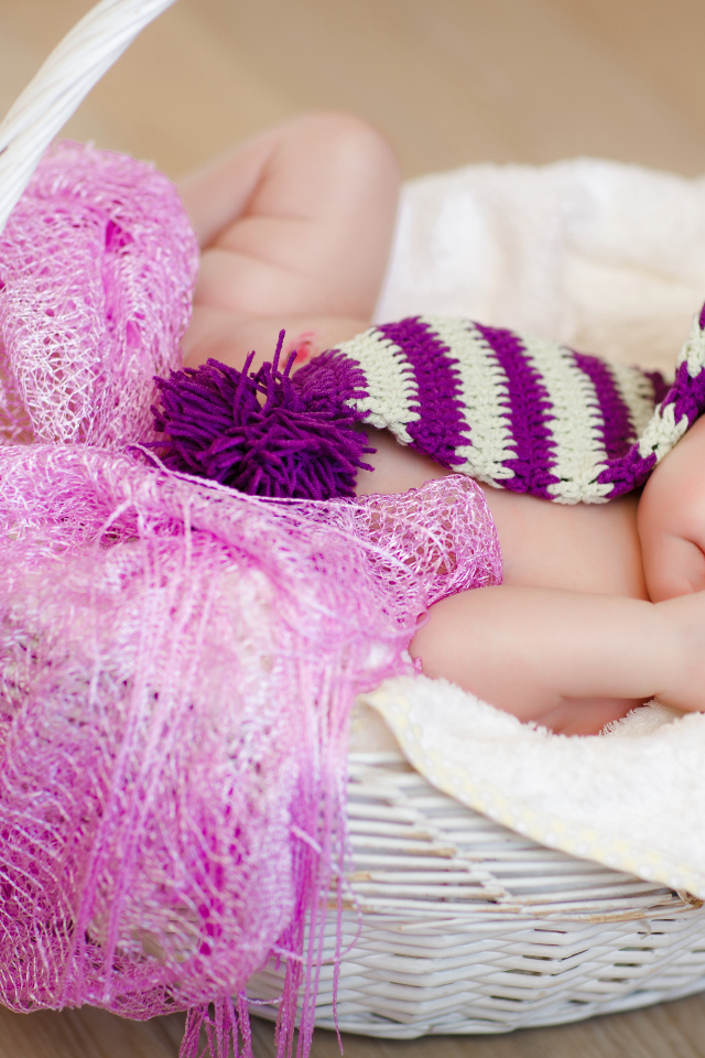 Младенец в красивой вязаной шапке лежит в корзине