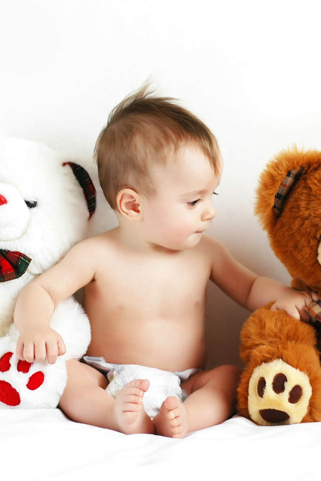 Младенец сидит с двумя большими плюшевыми медведями