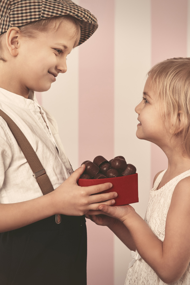 Мальчик дарит девочке коробку шоколадных конфет