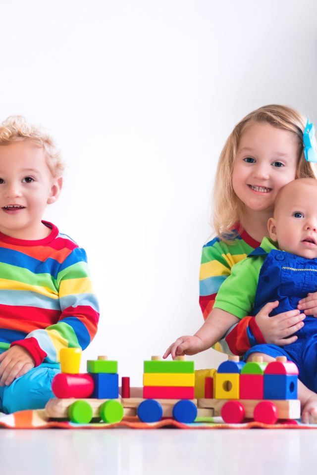 Три ребенка играют с игрушечным поездом