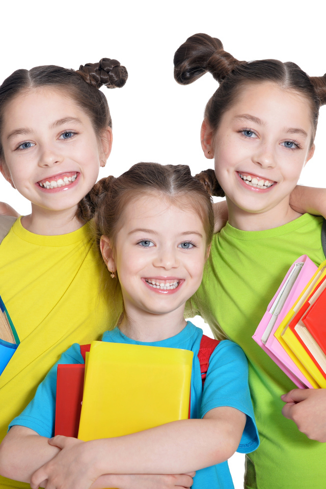 Три маленькие улыбающиеся девочки с книгами на белом фоне