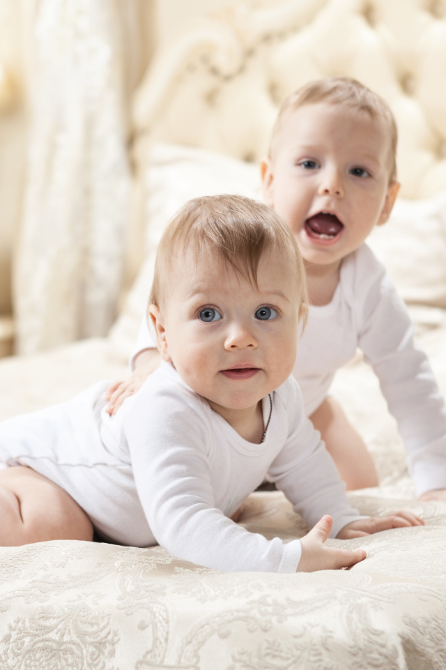 Два забавных младенца лежат на кровати