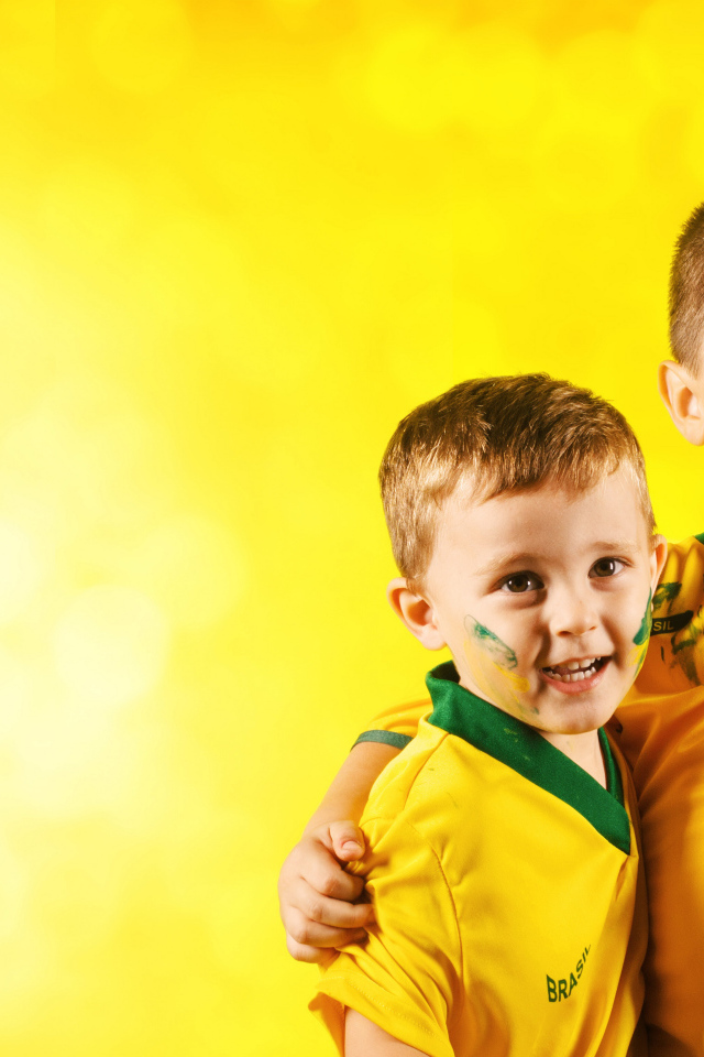 Два маленьких мальчика в спортивной форме на желтом фоне