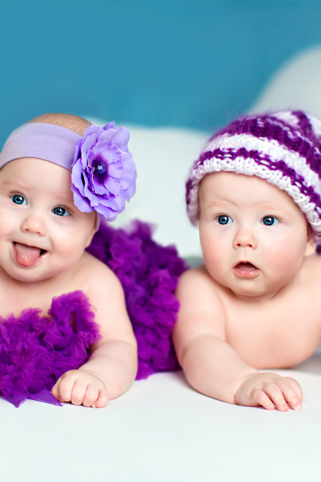 Два маленьких забавных младенца в красивых фиолетовых костюмах