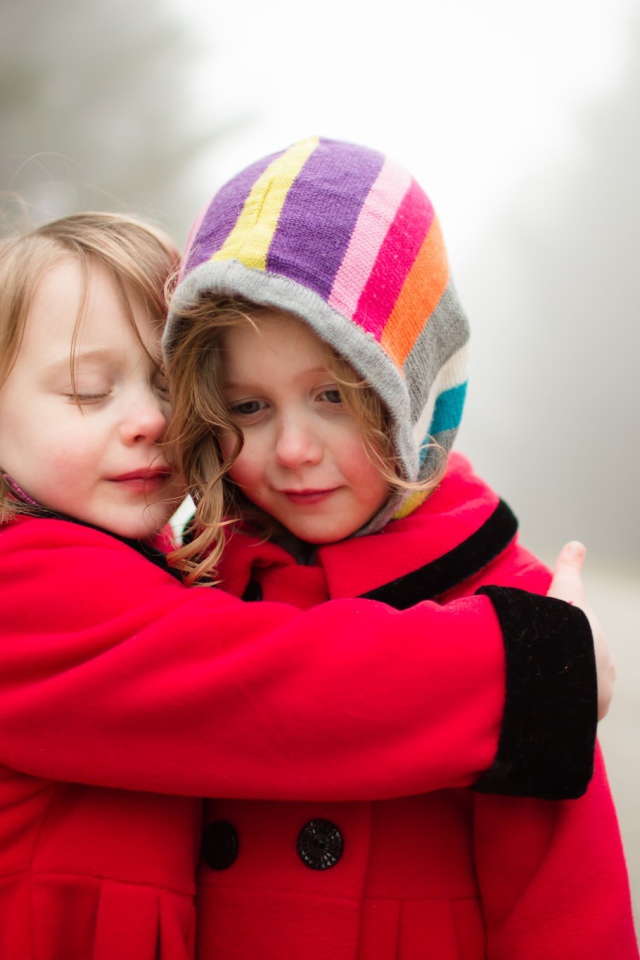 Две маленькие девочки обнимают друг друга 