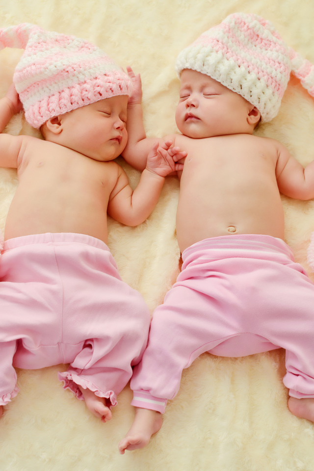 Два спящих грудных ребенка в розовых костюмах
