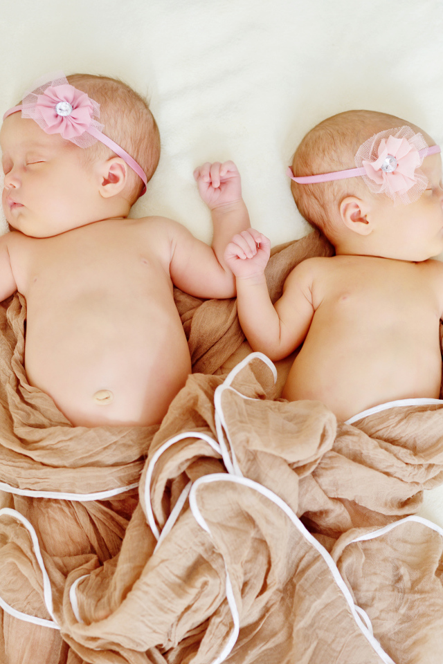 Два спящих младенца с розовыми цветами на голове