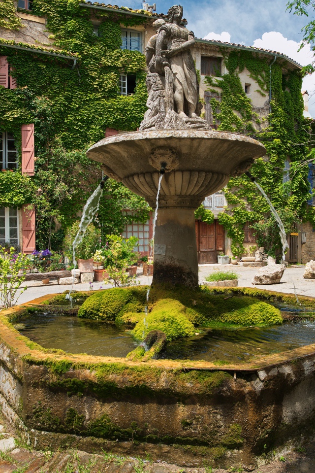 Старинный покрытый мхом фонтан на площади Сеньон, Франция