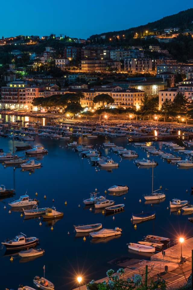 Panorama of a night city and a boat on the quay off the coast, Liguria. Italy