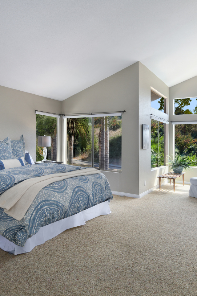 Уютная спальная комната в серых тонах с большими окнами